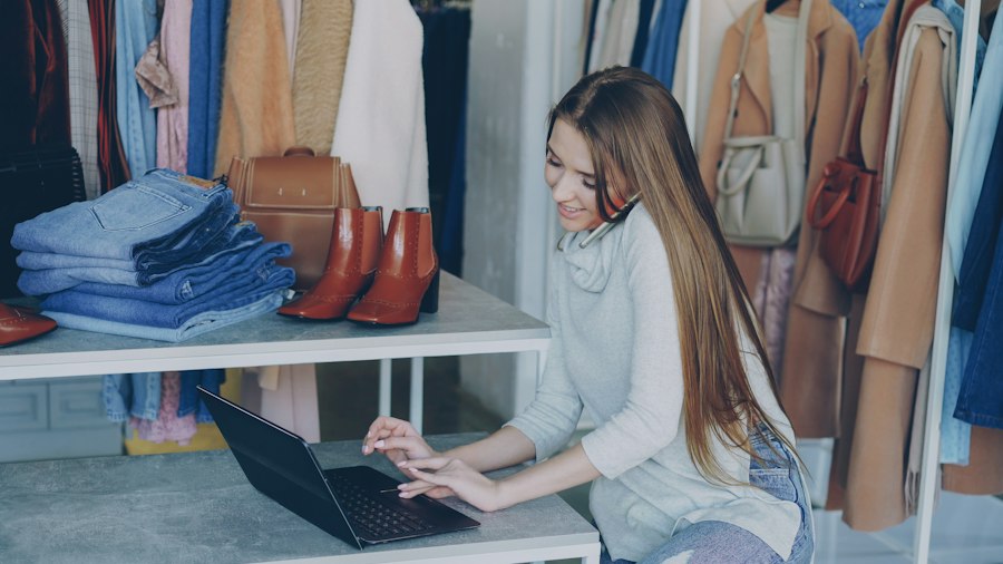 A shop owner working on a laptop in her clothing store