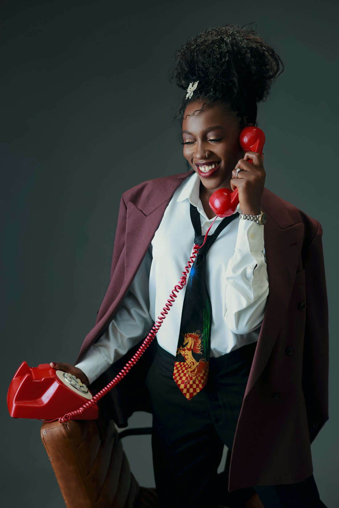A smiling woman holding a red telephone